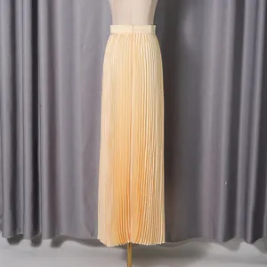 Detail view showing the fine pleats of an elegant high-waisted apricot maxi skirt.