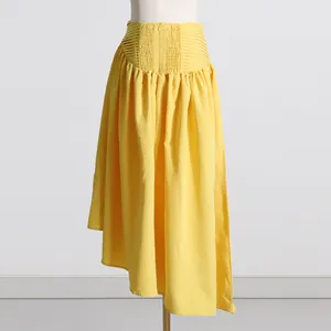 Detalle de una falda plisada amarilla de talle alto con textura nido de abeja