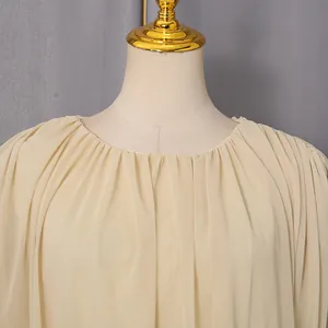 Close-up of elegant pleated round neckline on a beige French style dress.