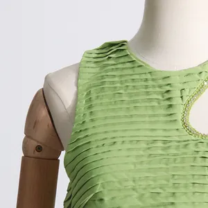 Primer plano del tejido plisado verde con detalle de abertura adornada con perlas