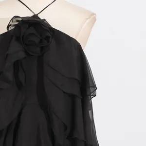 Close-up of elegant black halter neck maxi dress featuring 3D flower and ruffles.