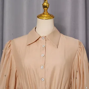 Detail view of beige French lapel dress with crystal buttons and rhinestone puff sleeves