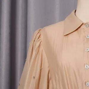 Detail of a French-style champagne dress with puff sleeves and rhinestone buttons.