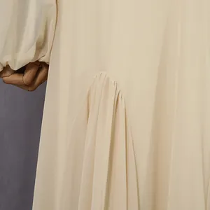 Close-up of elegant pleated detailing on a French style beige long dress.