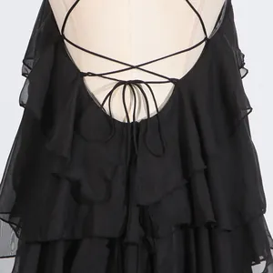 Detailed view of the layered ruffles and lace-up backless design of the black dress.