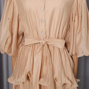 Detail of pleated beige French style dress with rhinestones and waist bow