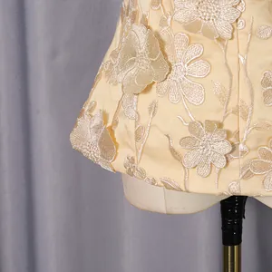 Detailed close-up of beige 3D floral appliqué on a light yellow elegant luxury top