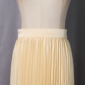 Detailed macro view showing the fine pleats and waistband of a champagne midi skirt