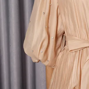 Close-up of pleated beige dress with rhinestone-embellished puff sleeves