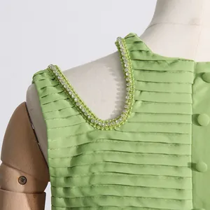 Primer plano detallado de blusa verde plisada con exquisito diseño de cuentas en hombros