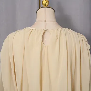 Close-up view of the back button closure and pleated fabric detail on an elegant beige dress