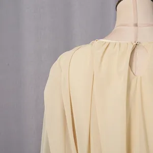 Detail view of the back keyhole neckline and delicate pleated fabric on an elegant beige gown.