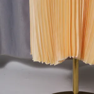 Detailed close-up view of the fine vertical pleats on a luxury yellow midi skirt hem