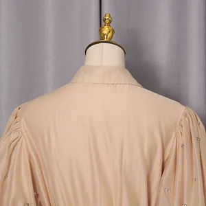Detail of the back collar and rhinestone puff sleeves on a chic beige French style maxi dress