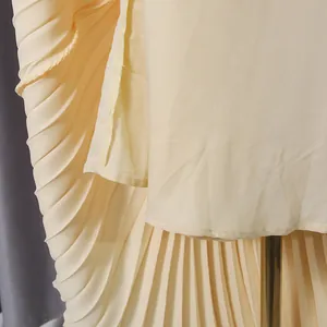 Detailed macro view showing the high-quality fine pleats and fabric of an elegant cream skirt