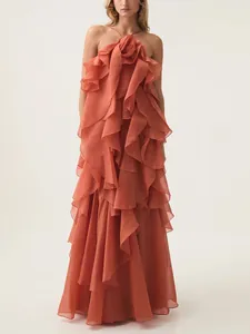 Elegant rust-orange ruffled halter maxi dress with 3D flower detail for 2026 spring collection.