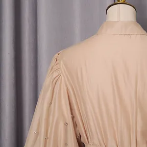 Close-up of elegant puff sleeves and rhinestone embellishments on a beige French dress