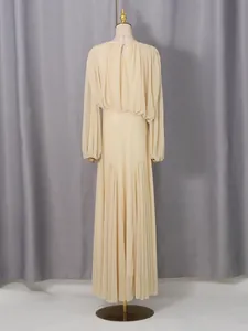 Back view of a long beige French style pleated dress on a mannequin with blouson sleeves