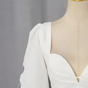 Detail van een witte Franse jurk met een hartvormige halslijn en opengewerkte borduring.