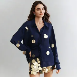Elegante camisa azul marino de manga larga combinada con minifalda de lentejuelas doradas.