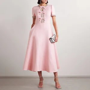 Nahaufnahme eines rosa Midikleides mit Kristall-Ausschnitt und eleganten Schleifen-Akzenten.
