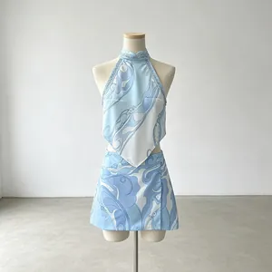 Two-piece resort set with blue abstract print halter top and matching mini skirt on mannequin.