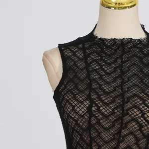 Close-up of elegant black lace dress with intricate geometric patterns and high neckline.