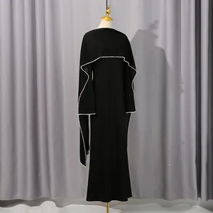 Elegant black evening dress featuring a pearl-trimmed shawl overlay on a mannequin