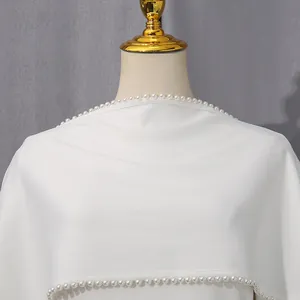Detailed view of an elegant white evening dress featuring sophisticated pearl beaded trim.