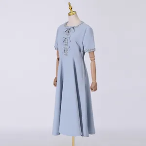 Detailansicht eines süßen hellblauen Midikleides mit Strass-Ausschnitt und Schleifen