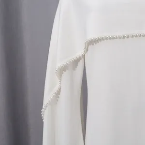 Detailed view of pearl trim on a white French-style long-sleeved evening dress shawl.