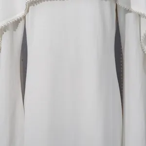 Close-up detail of white French style dress with elegant pearl trim and shawl design.