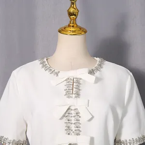 Nahaufnahme: eleganter weißer Kleidausschnitt mit glitzerndem Strass und Schleifen