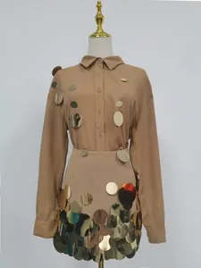 Conjunto de dos piezas de camisa beige de manga larga y minifalda de lentejuelas doradas.