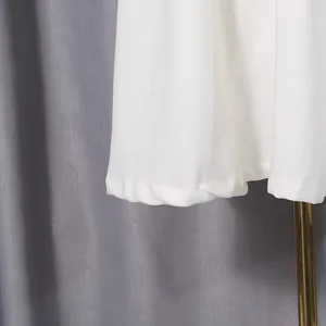 Detailansicht des weichen weißen Stoffes und Saums eines süßen langen Kleides für Damen.