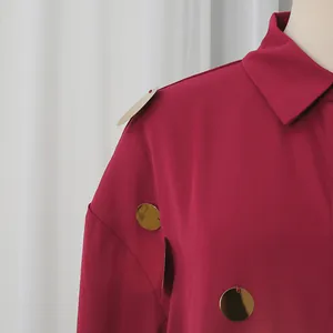Detalle de camisa de manga larga color burdeos con apliques de lentejuelas doradas