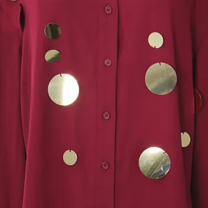 Detalle de camisa granate con lentejuelas doradas circulares y cierre de botones
