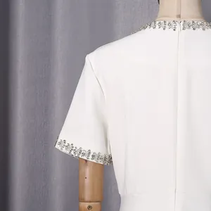 Nahaufnahme eines eleganten weißen Kleides mit glitzernden Strasssteinen an Ausschnitt und Ärmel