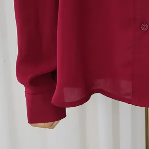 Primer plano del detalle de la blusa burdeos de manga larga, tejido suave y botones