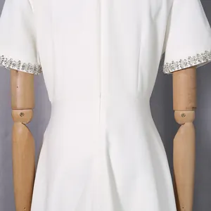 Detailansicht eines eleganten weißen Kleides mit verzierten Perlenmanschetten und Reißverschluss