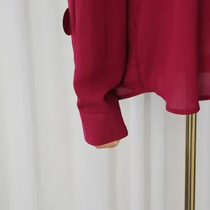 Primer plano del puño y dobladillo rojo vino en esta elegante blusa de gasa fina