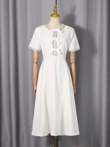 Elegant white midi dress with rhinestone neckline and bow details on mannequin