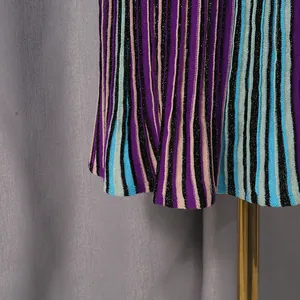 Close-up of the hem of a colorful striped knitted dress with fine vertical patterns.