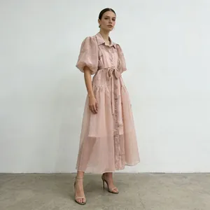 Elegante vestido midi bordado rosa palo con mangas abullonadas y cintura lazada.
