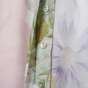 Detailed close-up of fresh floral print dress fabric featuring buttons and daisy patterns