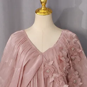 Détail d'une robe rose à col en V avec manches chauve-souris et appliqués floraux en 3D