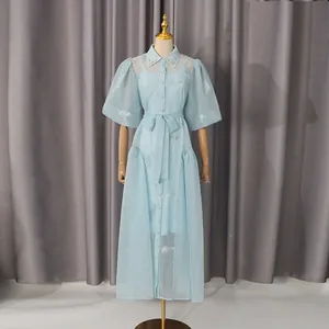 Detalle del vestido de malla bordada en azul claro con mangas abullonadas y lazo en la cintura