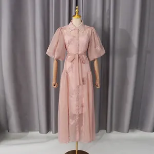 Vista completa de un vestido rosa bordado con mangas abullonadas y cintura anudada