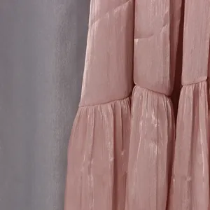 Détail de la texture satinée rose chatoyante et froissée de cette robe de vacances romantique