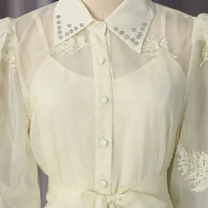 Vista detallada de un elegante vestido crema con cuello de pedrería y bordado de hojas